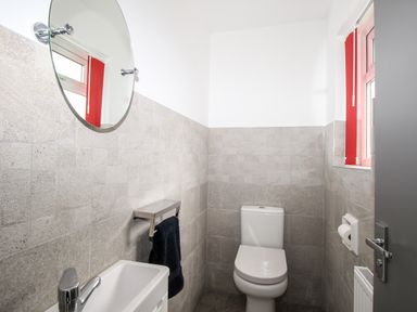 A small bathroom with a toilet sink mirror and towel rack at Rosamond in Shipton Gorge