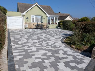 A driveway with a patterned surface and outdoor table set in front of a house at Rosamond in Shipton Gorge