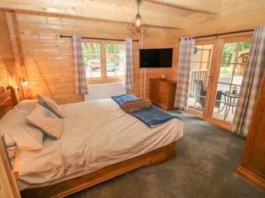 A bedroom with a bed pillows dresser and a television at Bryn Derwen Lodge in Bethesda