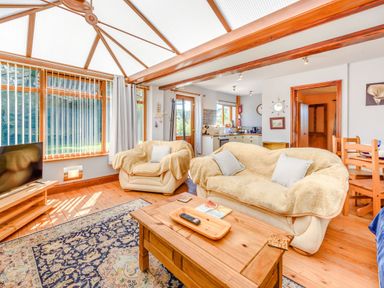 A living room with sofas a wooden coffee table a television and a kitchen in the background at Covert Farm Cwtch in Jeffreyston
