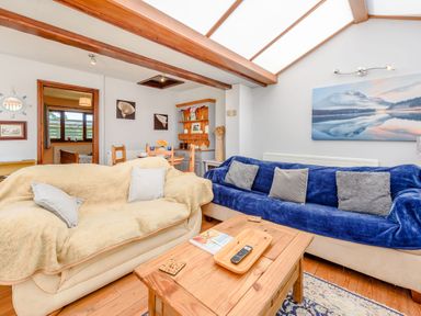 A living room with two sofas a wooden coffee table and a dining area at Covert Farm Cwtch Jeffreyston