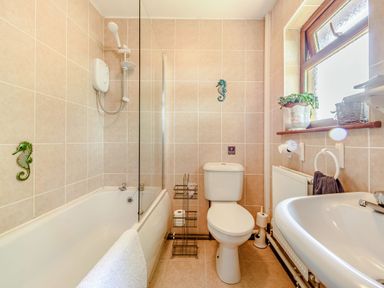 A bathroom with a bathtub shower toilet sink and a window with a potted plant at Covert Farm Cwtch in Jeffreyston