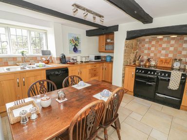A kitchen with wooden cabinets and dining table with four chairs at Spring Cottage in Alkerton near Banbury