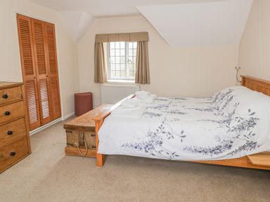A bedroom with a bed a wooden chest a wooden dresser and a window with curtains at Spring Cottage in Alkerton near Banbury
