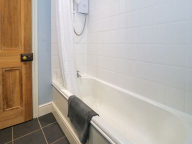 A bathroom with a bathtub and shower curtain at Sygun View in Beddgelert