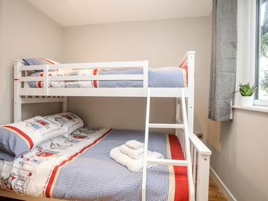 A bedroom with a white bunk bed with patterned bedding and towels on the bottom bed at Laneton in Rhosneigr