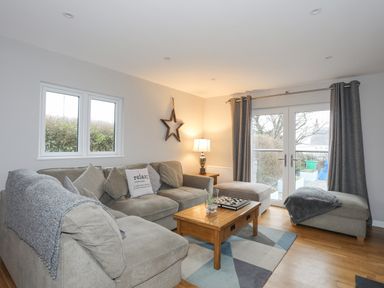 A living room with a grey sectional sofa and wooden coffee table at Laneton in Rhosneigr