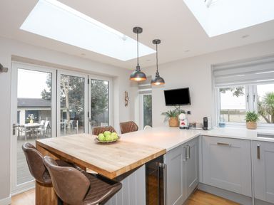 A kitchen with a wooden table and brown chairs under skylights at Laneton in Rhosneigr