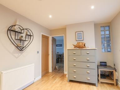 A hallway with wooden doors a chest of drawers and a heart shaped shelf on the wall at Laneton in Rhosneigr