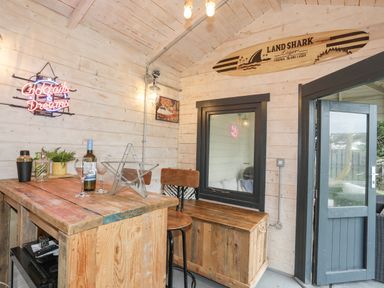 A wooden bar area with a wooden table stools a bench and a door leading outside at Laneton in Rhosneigr