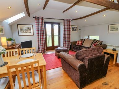 A sitting room with two sofas a wooden dining table with chairs and plaid curtains at Field Barn in Alston