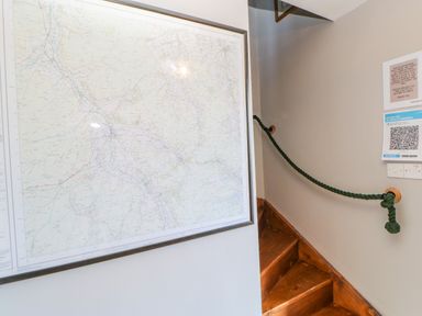A framed map on a wall next to wooden stairs with a green rope handrail at Field Barn in Alston