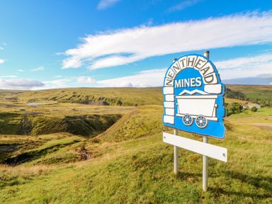 A sign for nenthead mines on a grassy hill with rolling hills and a blue sky in the background at Field Barn in Alston