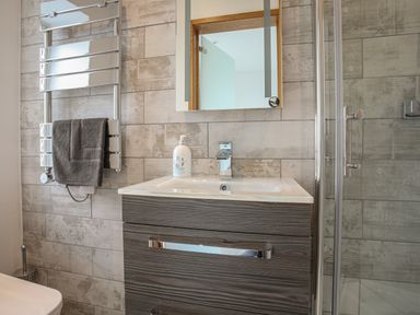 A bathroom sink with a mirror above and a towel hanging on a chrome rail at Hafod Y Mor in Criccieth