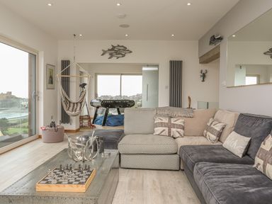 A living room with sectional sofa chess board and hanging chair at Hafod Y Mor in Criccieth