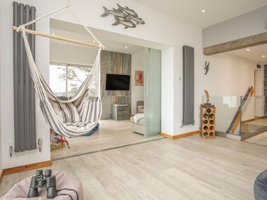 An interior room with a hanging chair and a television on a wall at Hafod Y Mor in Criccieth