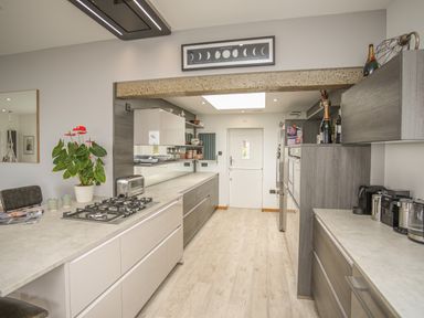 A kitchen with gas hob coffee machines and cabinets with a plant on the counter at Hafod Y Mor in Criccieth