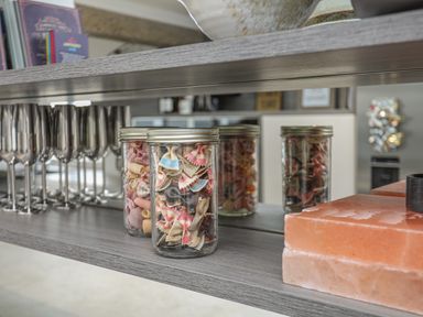A kitchen shelf with jars of colorful pasta and metal wine glasses at Hafod Y Mor in Criccieth