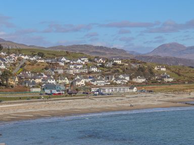 A coastal town with houses on a hillside near a beach and the sea at Hafod Y Mor in Criccieth