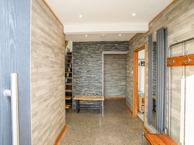 An entrance hallway with a bench a mirror and a coat rack at Hafod Y Mor in Criccieth