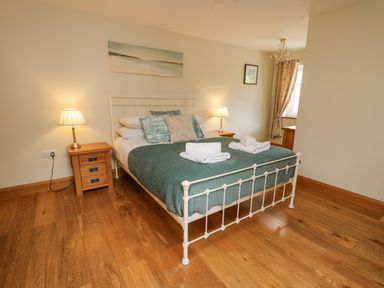 A bedroom with a white metal bed frame and a green quilted bedspread at Yr Hen Beudy in Capel Bangor