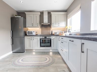 A kitchen with grey cabinets and countertops a refrigerator and a microwave at Cartref in Trawsfynydd