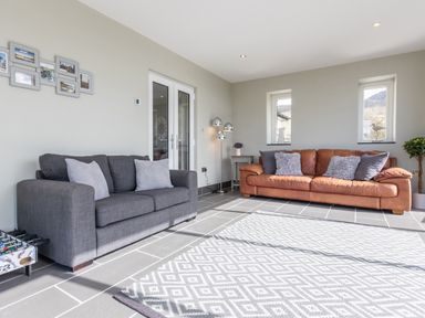 A living room with two sofas cushions a floor lamp a small table and a patterned rug at Cartref in Trawsfynydd