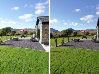 An outdoor seating area with a red umbrella and stone wall near a grassy lawn and hills at Cartref in Trawsfynydd