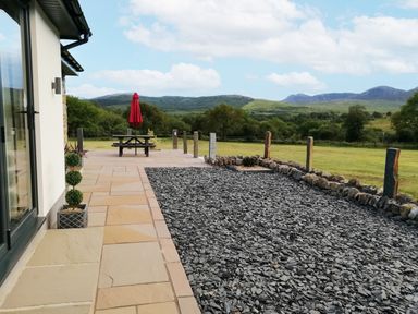 A patio with a picnic table and an umbrella at Cartref Trawsfynydd