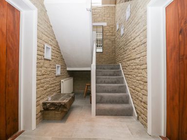 A stairway with stone walls and carpeted steps between two wooden doors at The Linhay in Chardstock