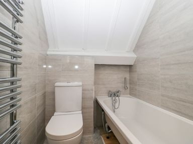 A bathroom with a toilet a bathtub and a chrome heated towel rail at The Linhay in Chardstock