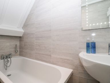 A bathroom with a bathtub a sink and two bottles on the sink at The Linhay in Chardstock