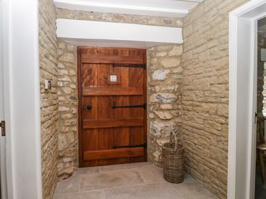 A wooden door set in a stone wall with a wicker basket on the floor at The Linhay in Chardstock