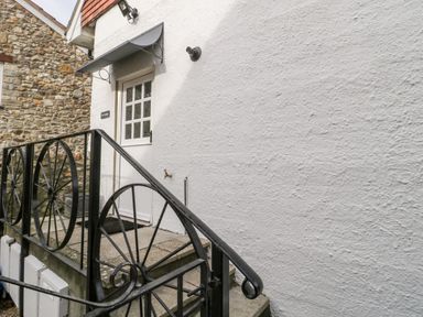 A white door with multiple glass panes above steps with a black metal railing outside a building at The Linhay in Chardstock