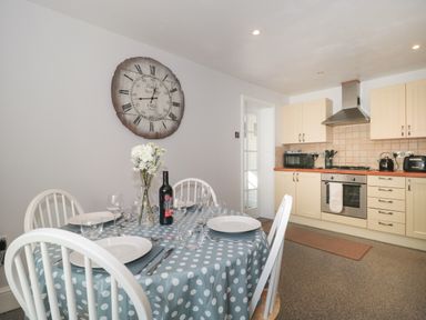 A kitchen with a dining table set with plates glasses and a bottle of wine at The Linhay in Chardstock
