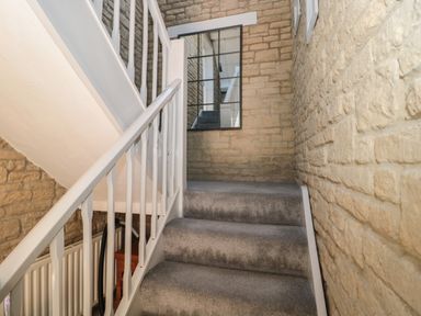 A staircase with gray carpet white railings stone brick walls and a window at The Linhay in Chardstock