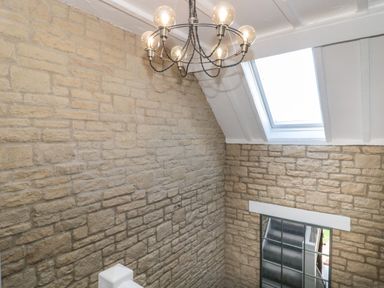 A stairway with stone walls a window a skylight and a chandelier at The Linhay in Chardstock
