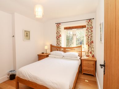 A bedroom with a wooden bed and two bedside tables with lamps at Puffin Cottage in Hawkchurch