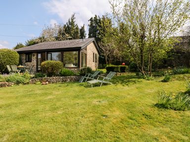 A garden with lawn chairs trees shrubs and a stone cottage at Puffin Cottage in Hawkchurch