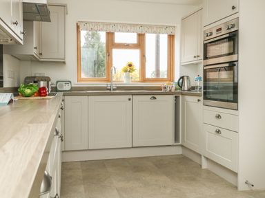 A kitchen with cabinets a double oven a kettle and vegetables on the counter at Gabrianne in Burton Bradstock