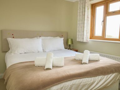 A bedroom with a bed with white pillows and towels and a window at Gabrianne in Burton Bradstock