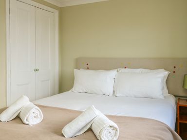 A bedroom with a bed made with white linens and rolled towels at Gabrianne in Burton Bradstock