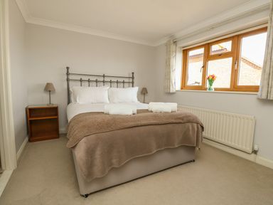 A bedroom with a bed two bedside tables with lamps a window and a radiator at Gabrianne in Burton Bradstock