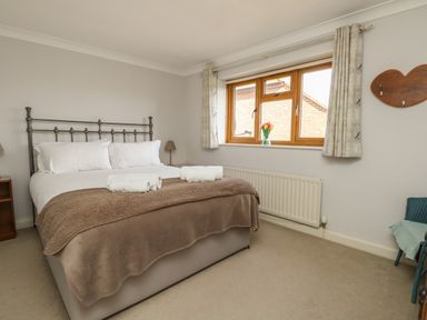 A bedroom with a double bed and a window with curtains at Gabrianne in Burton Bradstock