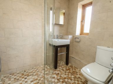 A bathroom with a sink mirror window toilet and glass shower door at Gabrianne in Burton Bradstock
