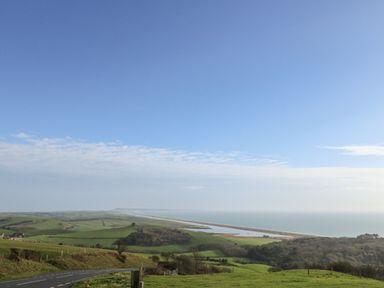 A coastal landscape with green fields a road and the sea at Gabrianne in Burton Bradstock