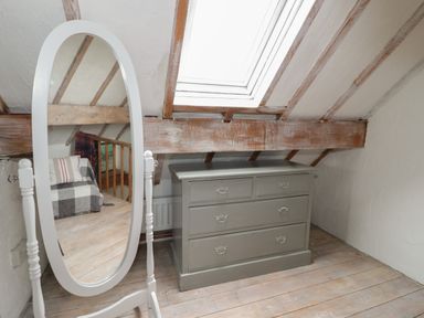 A room with a standing oval mirror and a chest of drawers under a skylight at Little House in Red Wharf Bay