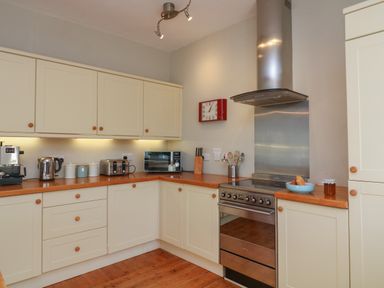 A kitchen with cream cabinets wooden countertops a stainless steel oven and hood and appliances on the countertop at 1 Bailey's Cottage in Stoke Fleming