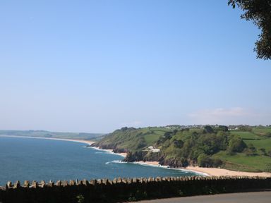 A coastal landscape with a beach ocean cliffs and green hills at 1 Bailey's Cottage in Stoke Fleming