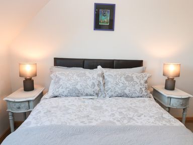 A bedroom with a bed that has floral bedding and two bedside tables with lamps at Whinstones at 4 The Villas in Embleton